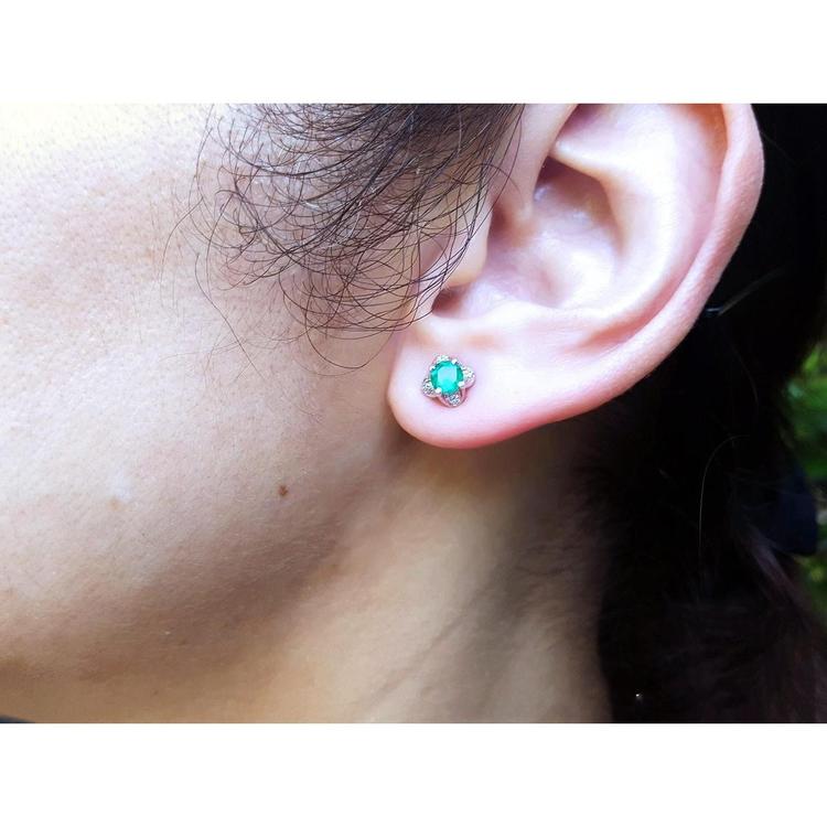 Emerald and diamond tulip stud earring in 14K white gold worn on an ear.
