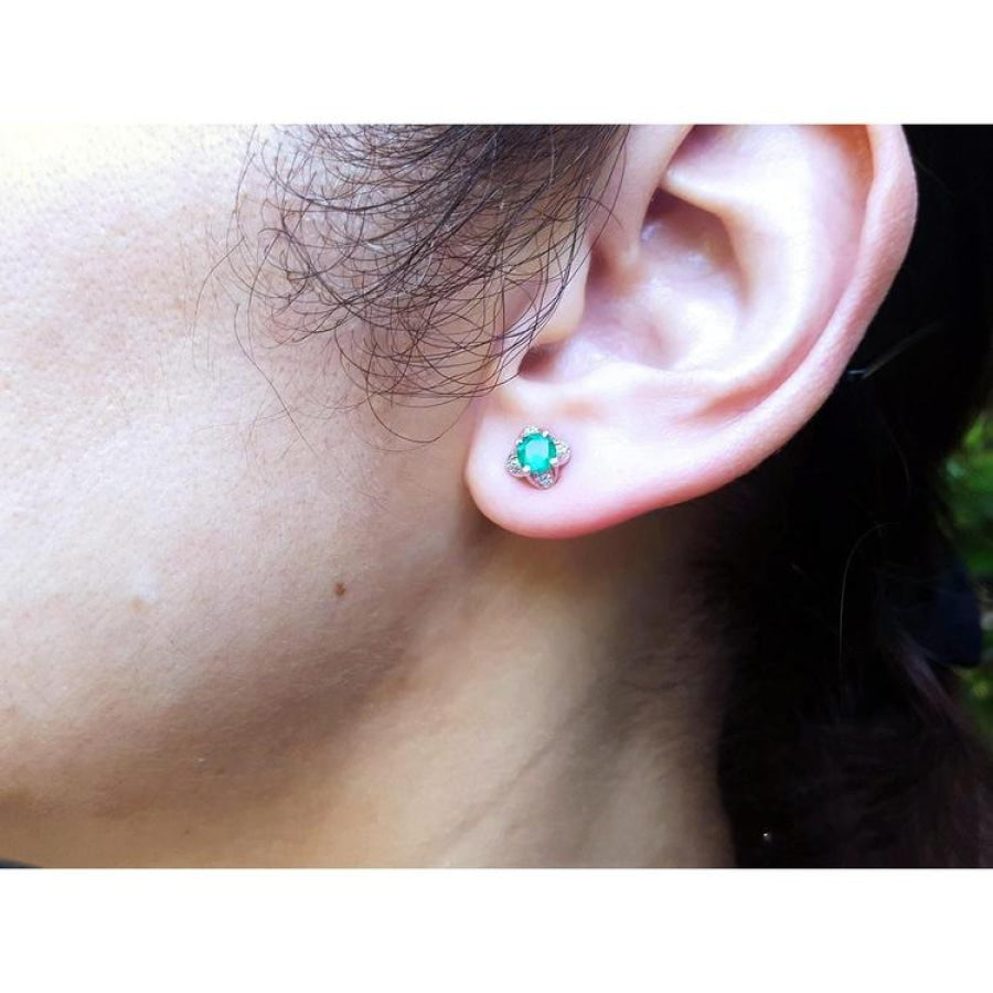 Emerald and diamond tulip stud earring in 14K white gold worn on an ear.