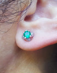 Close-up of an ear with a emerald and diamond tulip stud earring.