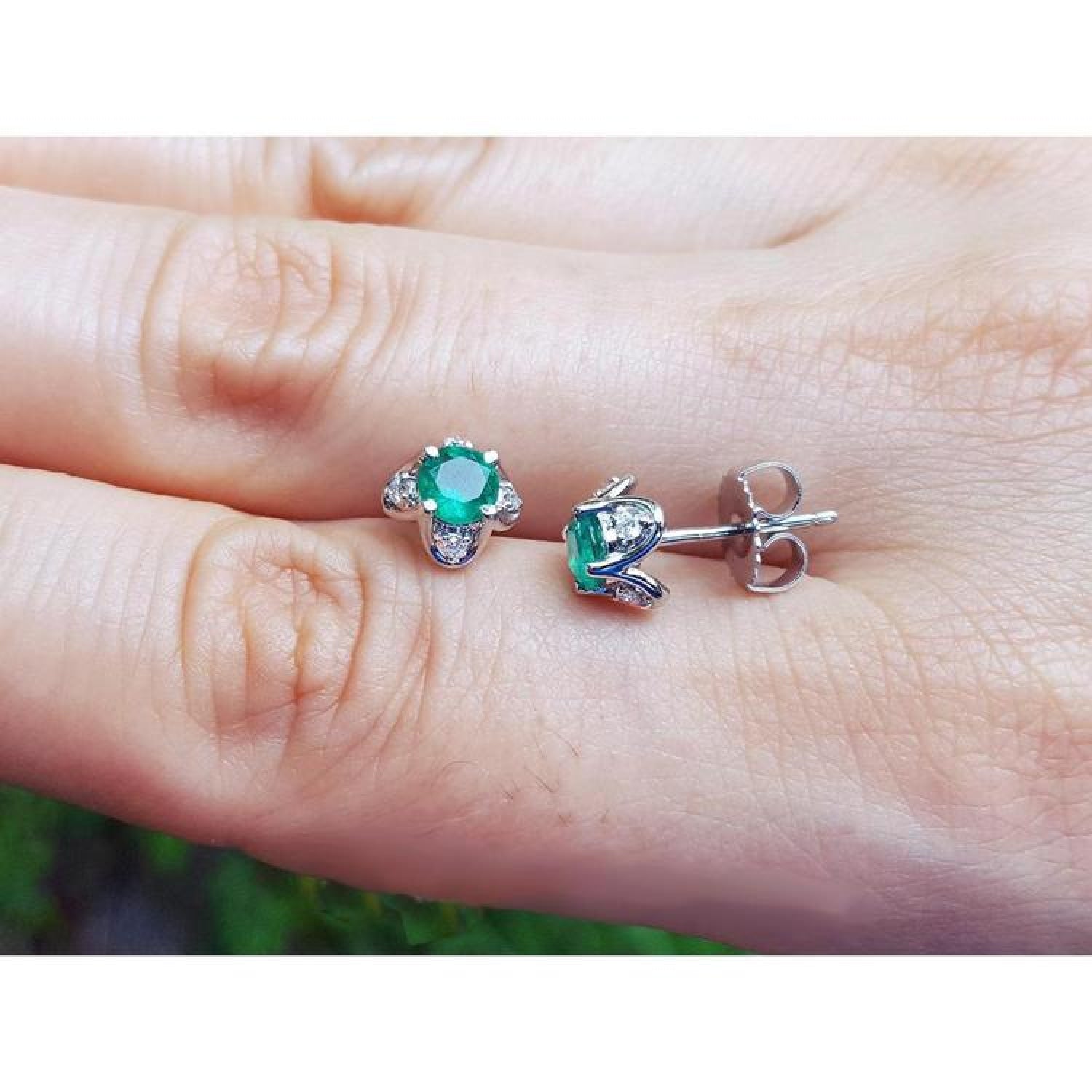 Emerald and diamond tulip stud earrings in 14K white gold, featuring deep bluish-green emeralds and accent diamonds.