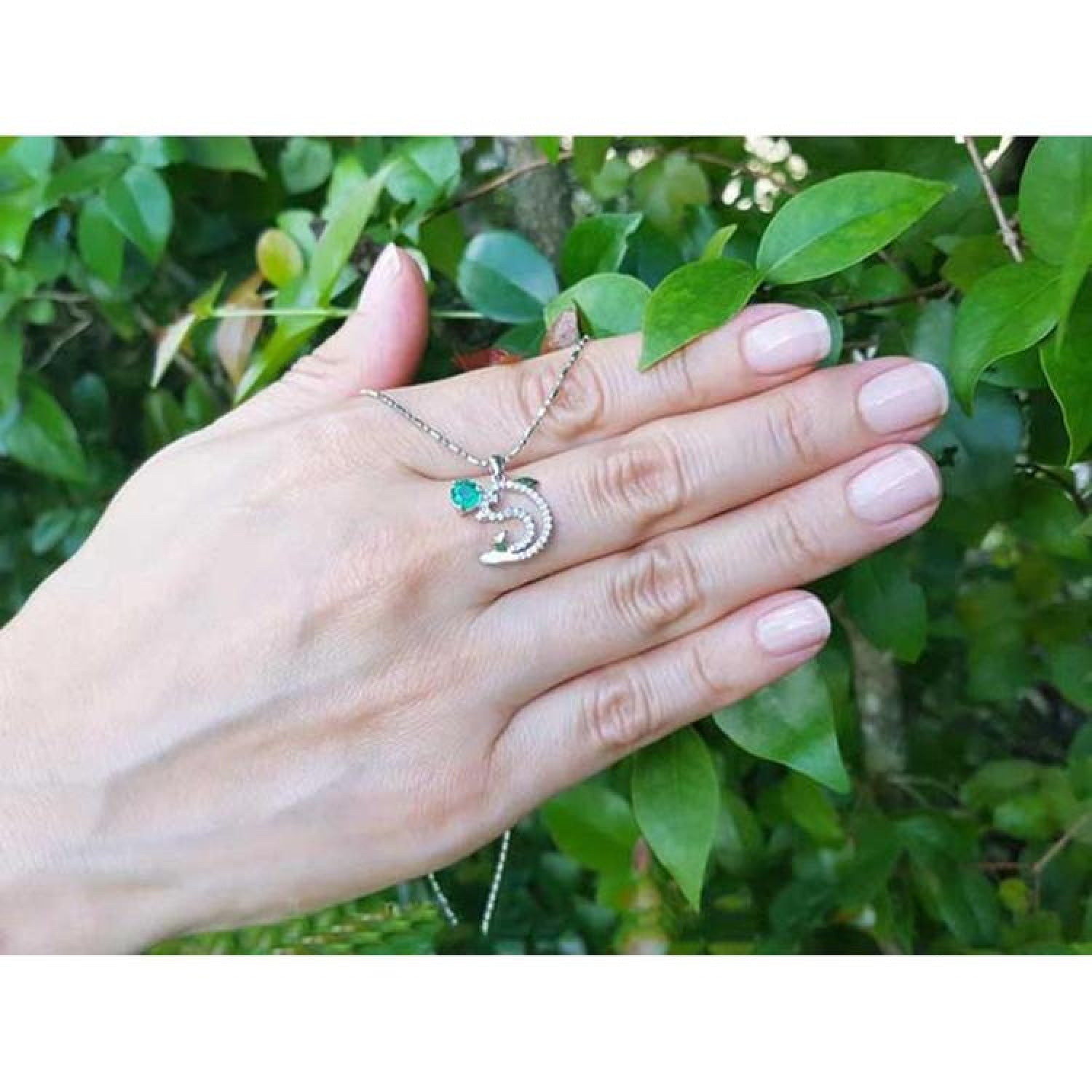 14K white gold dolphin pendant necklace with a brilliant round Colombian emerald on a hand.