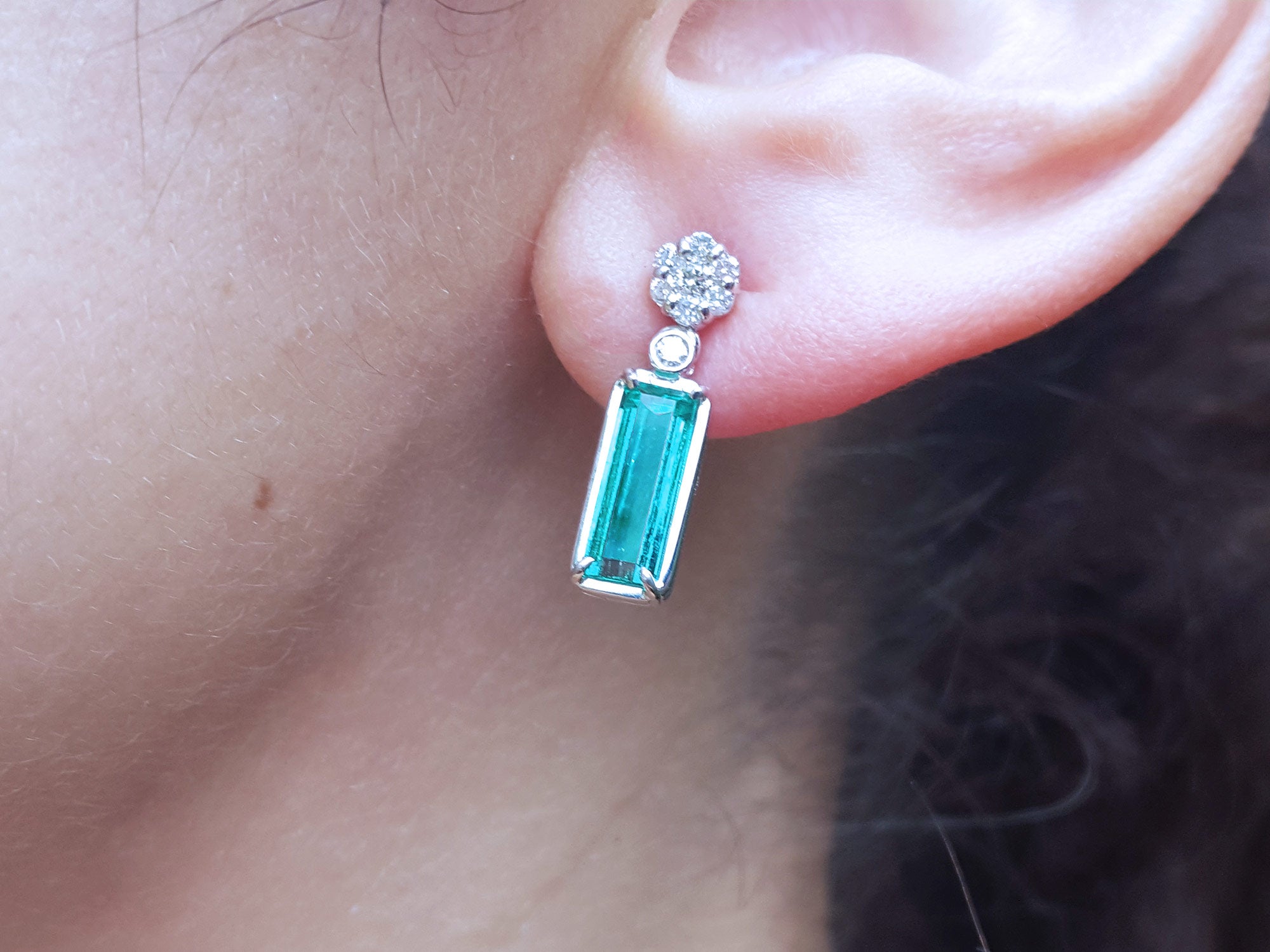 Emerald baguette cut earring worn on an ear with a blurred background