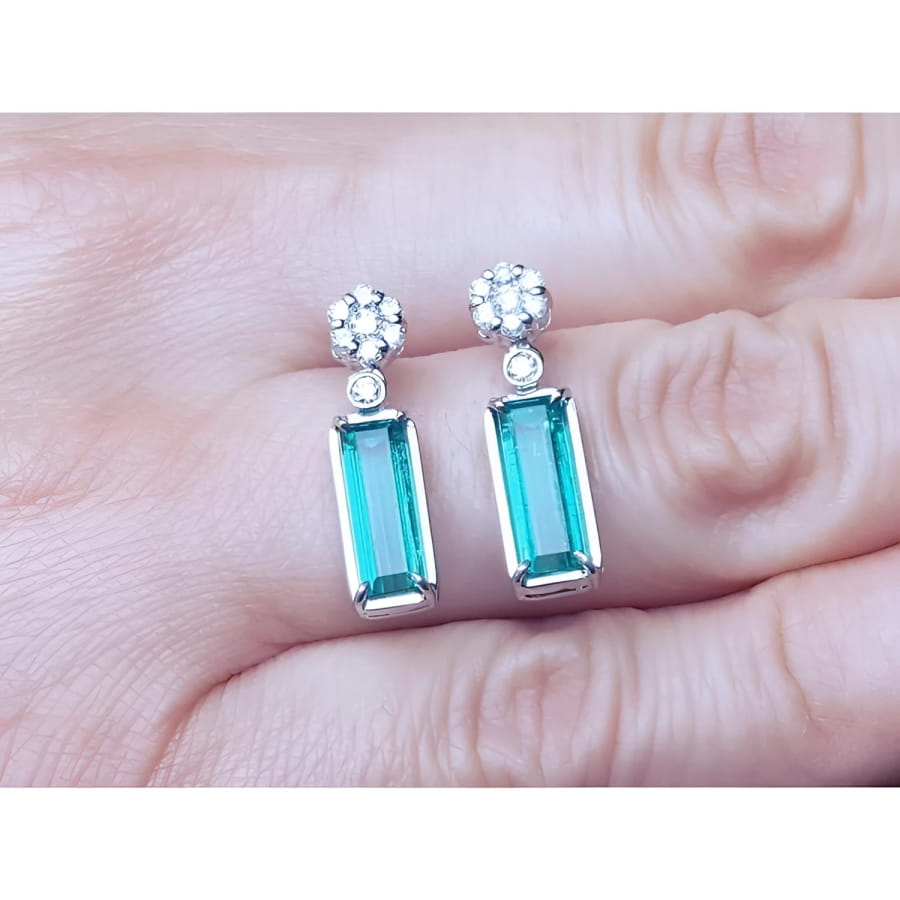 14K white gold dangling earrings with rectangular emeralds and diamond clusters.