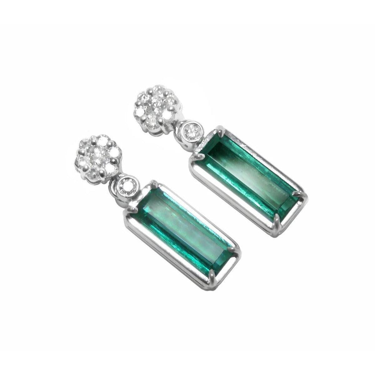 Pair of earrings with rectangular emeralds suspended fron a cluster diamonds accents on a white background