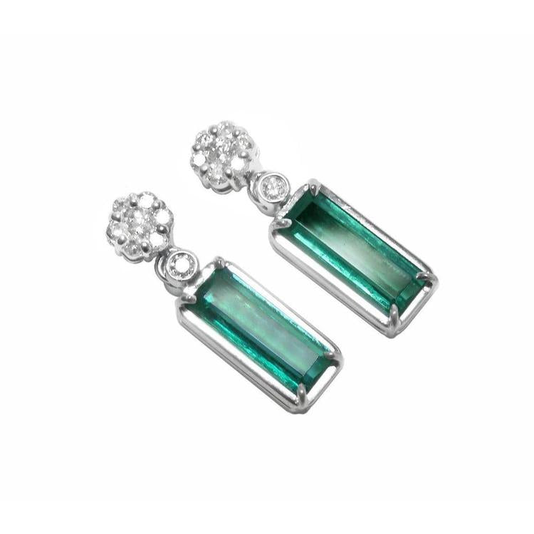 Pair of earrings with rectangular emeralds suspended fron a cluster diamonds accents on a white background