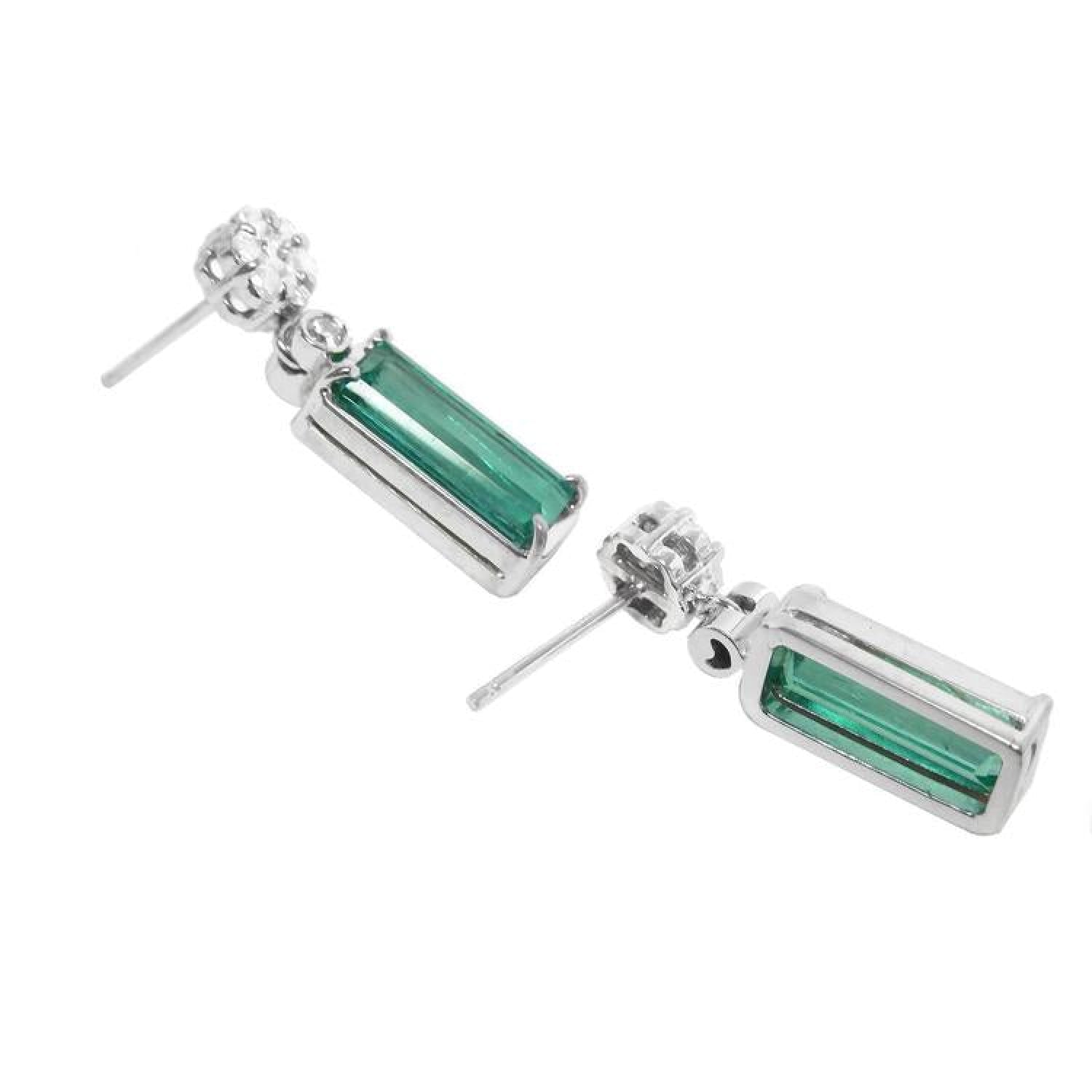 14K white gold dangling earrings with rectangular emeralds and diamond clusters.