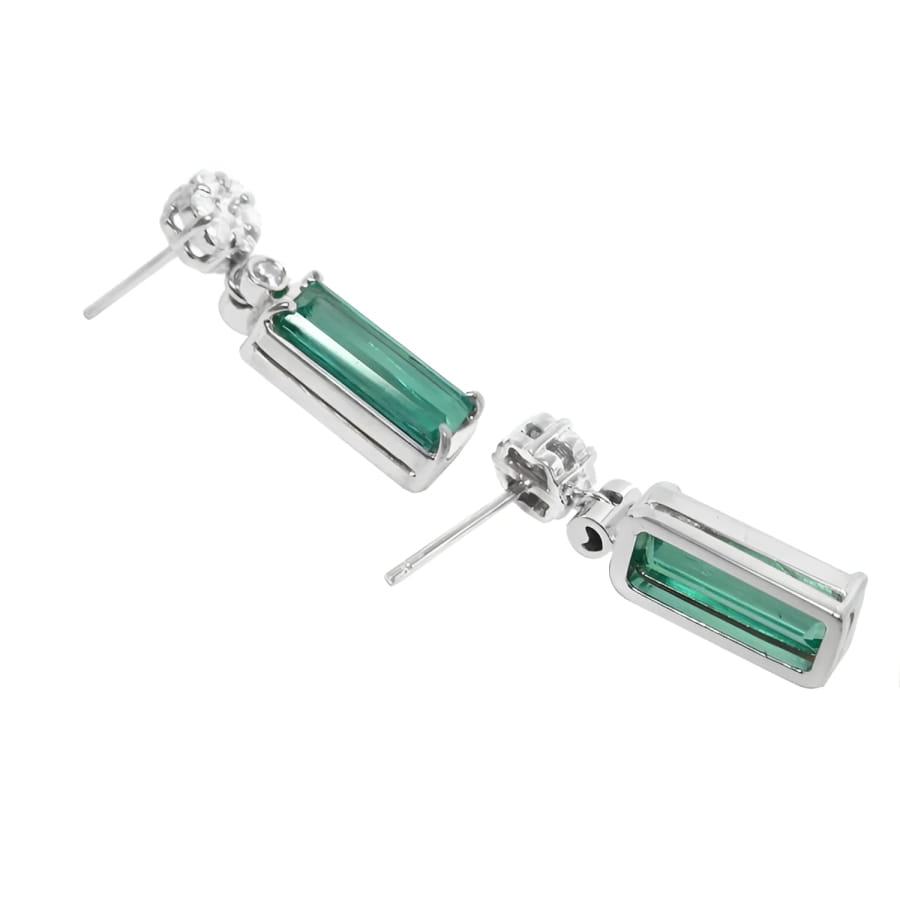 14K white gold dangling earrings with rectangular emeralds and diamond clusters.