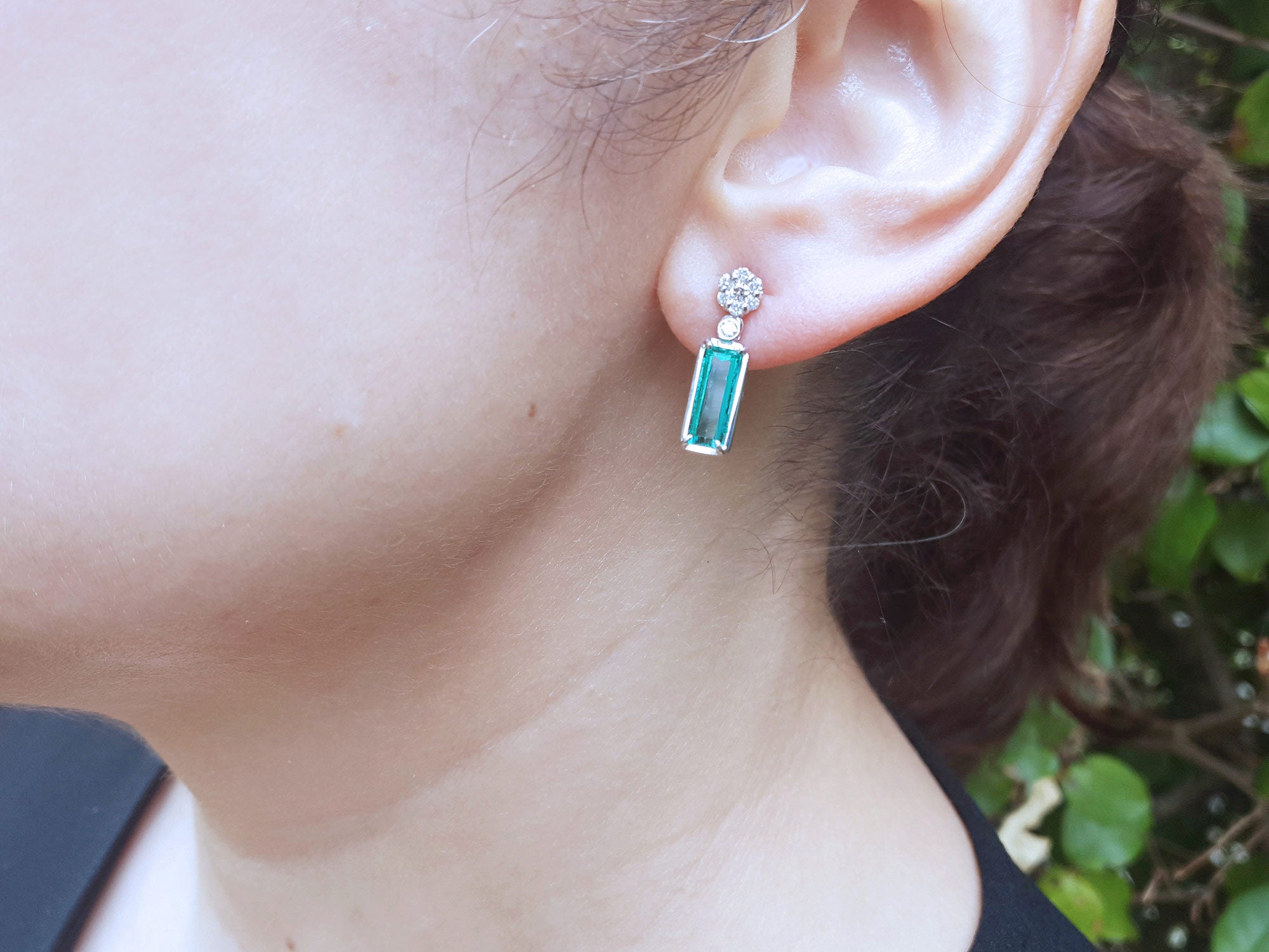 Close-up of a woman&#39;s face wearing a natural emerald earring with a blurred background