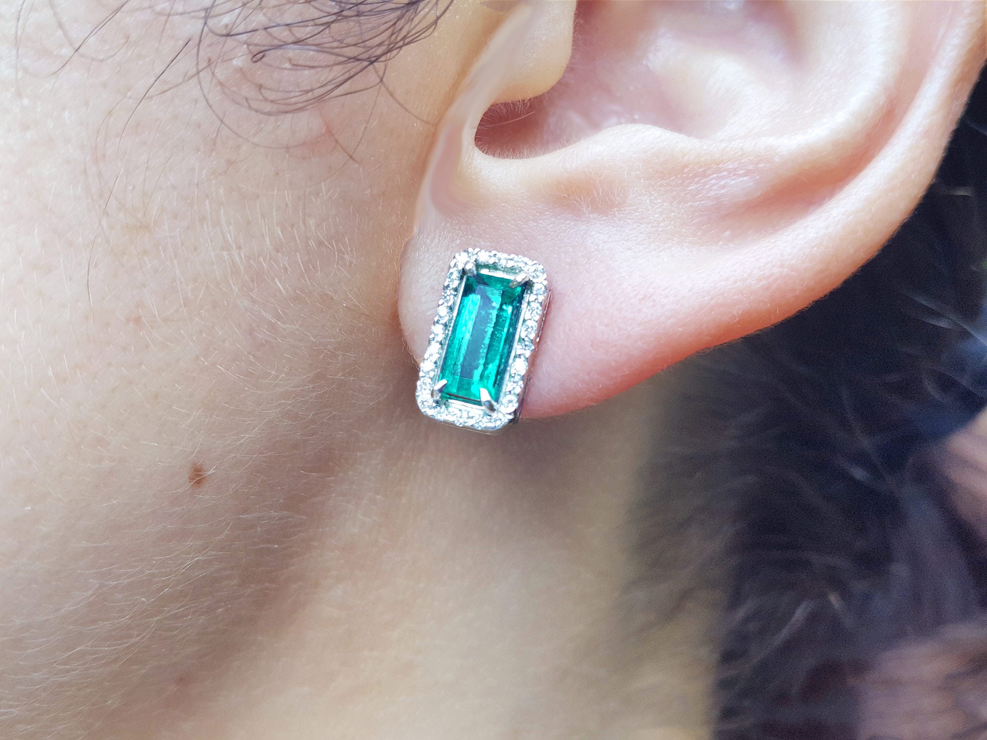 Emerald earring halo diamond in white gold on a woman&#39;s ear