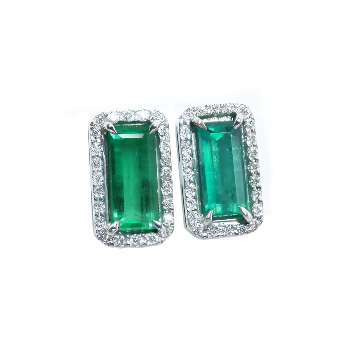 Pair of natural colombian emerald earrings with 18k white gold frames and halo diamond.