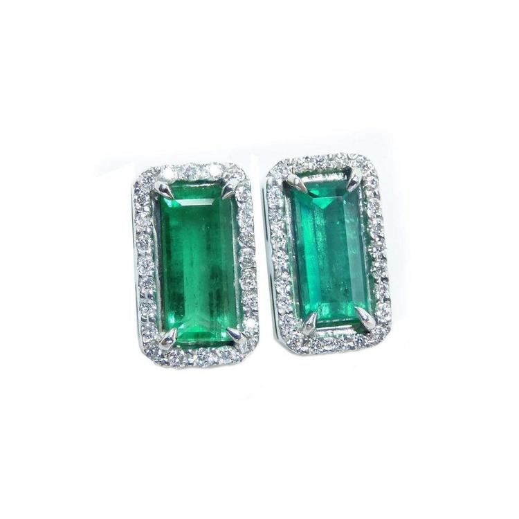 Pair of natural colombian emerald earrings with 18k white gold frames and halo diamond.