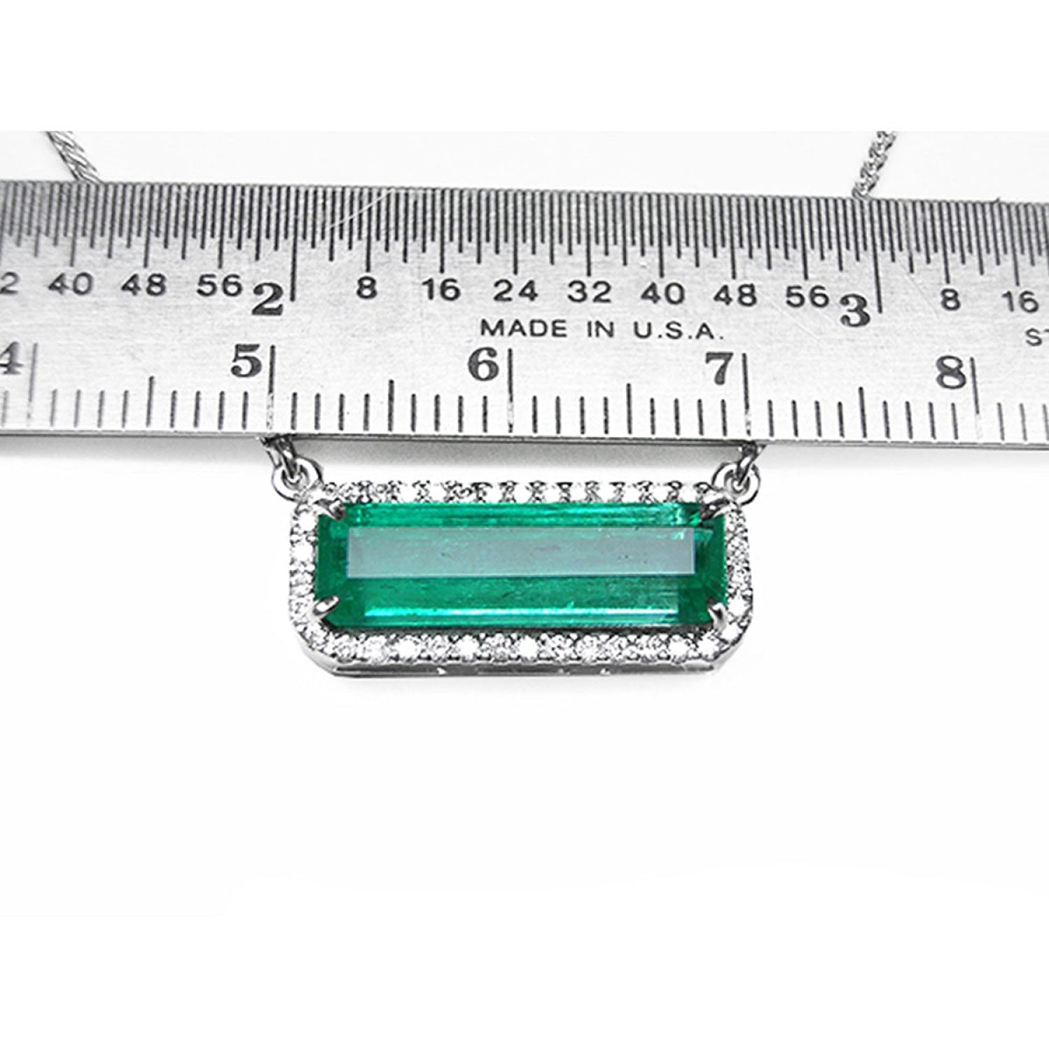 18K white gold Colombian emerald necklace with halo diamonds, East-West rectangular design, shown below a metal ruler for scale.