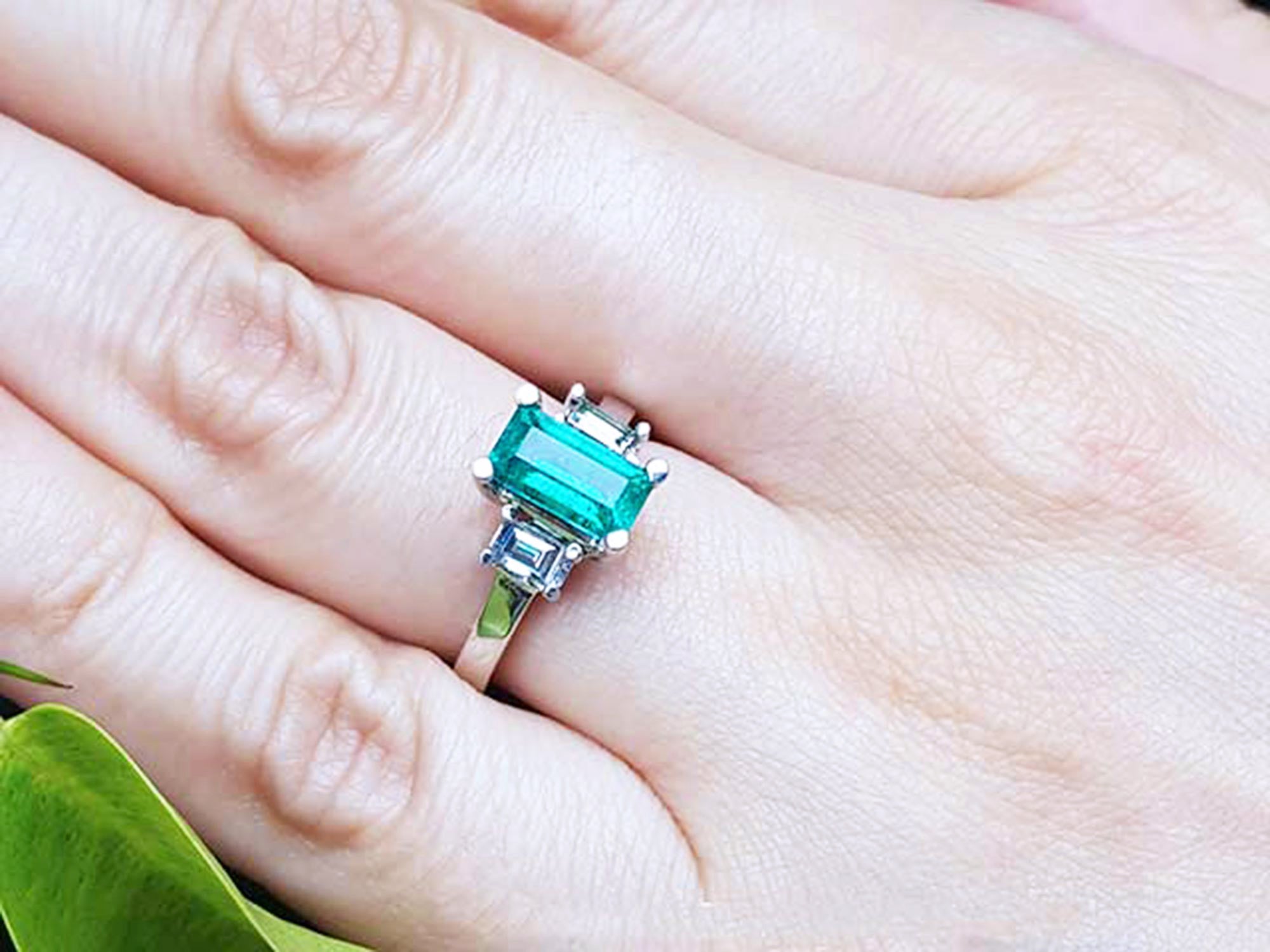 Green gemstone ring on a finger with a blurred background