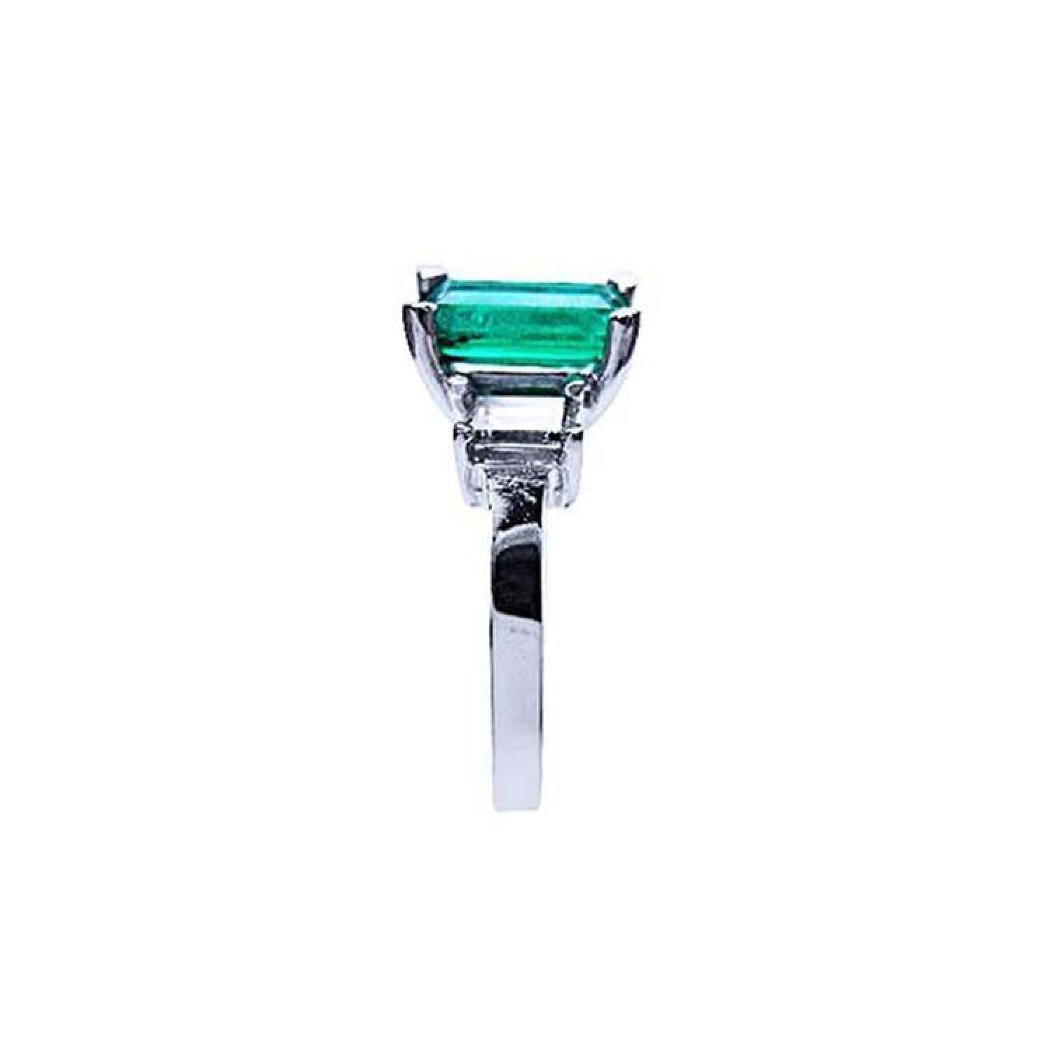 Emerald cut Colombian emerald engagement ring in 18K white gold with baguette diamond accents.