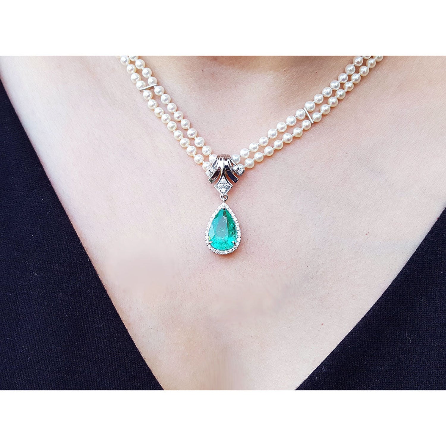 Pear-shaped emerald enhancer necklace with halo diamonds, dangling from a double strand pearl necklace.