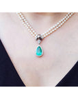 Pear-shaped emerald enhancer necklace with halo diamonds, dangling from a double strand pearl necklace.