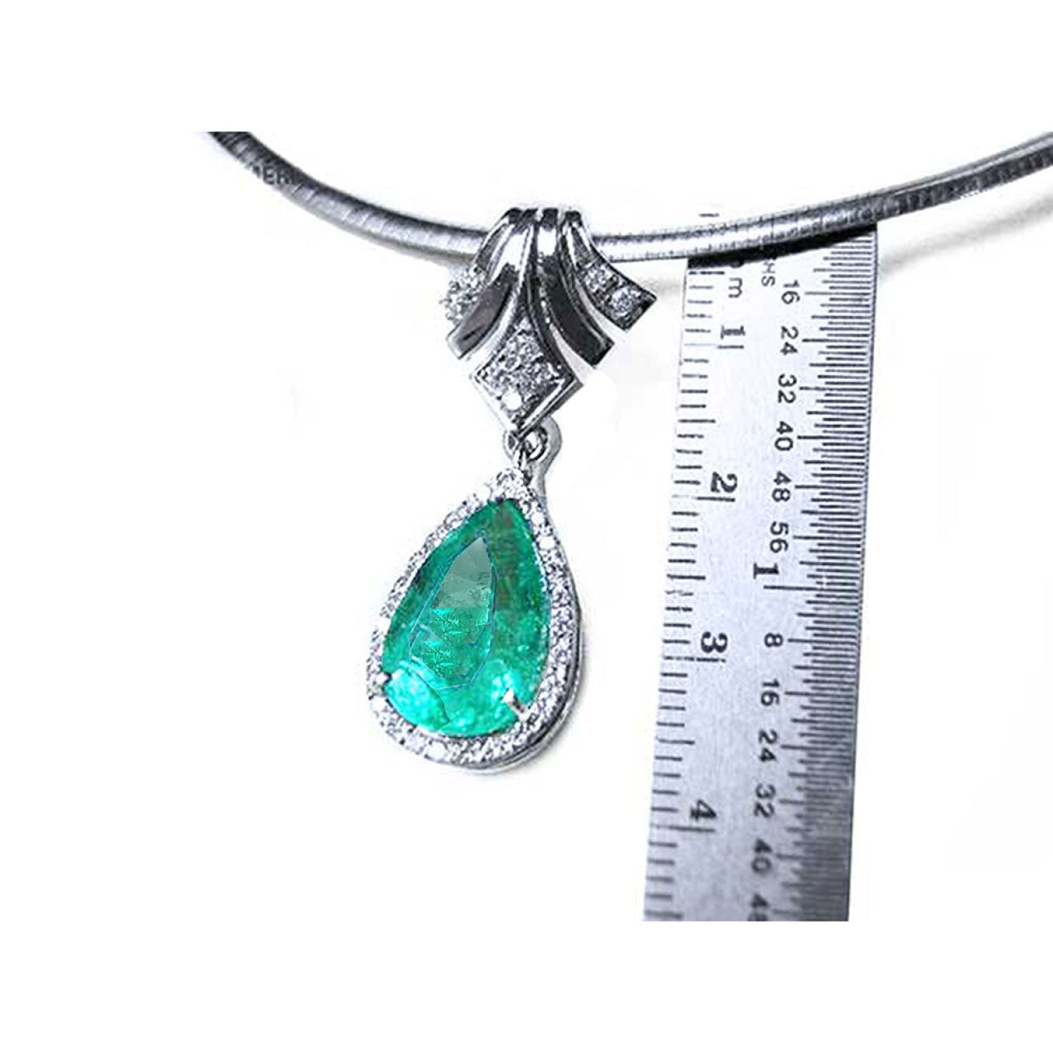 18K white gold enhancer necklace with a pear-shaped emerald and halo diamonds, measured against a ruler.