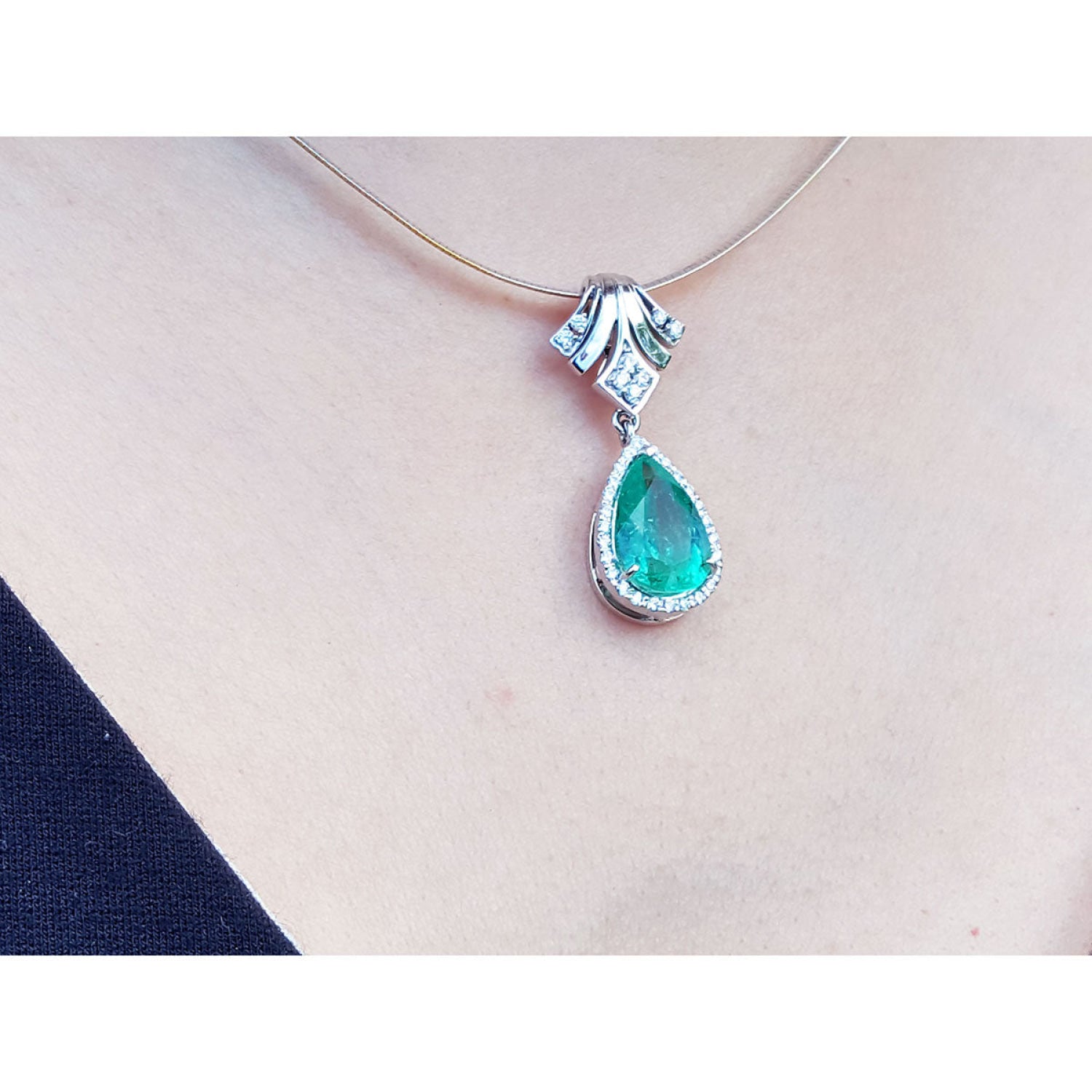 18K white gold enhancer necklace with a pear-shaped emerald and halo diamonds on a thin choker.