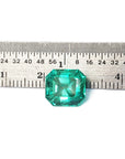 4.71 carat emerald-cut Colombian emerald, medium bluish-green, next to a ruler for scale.