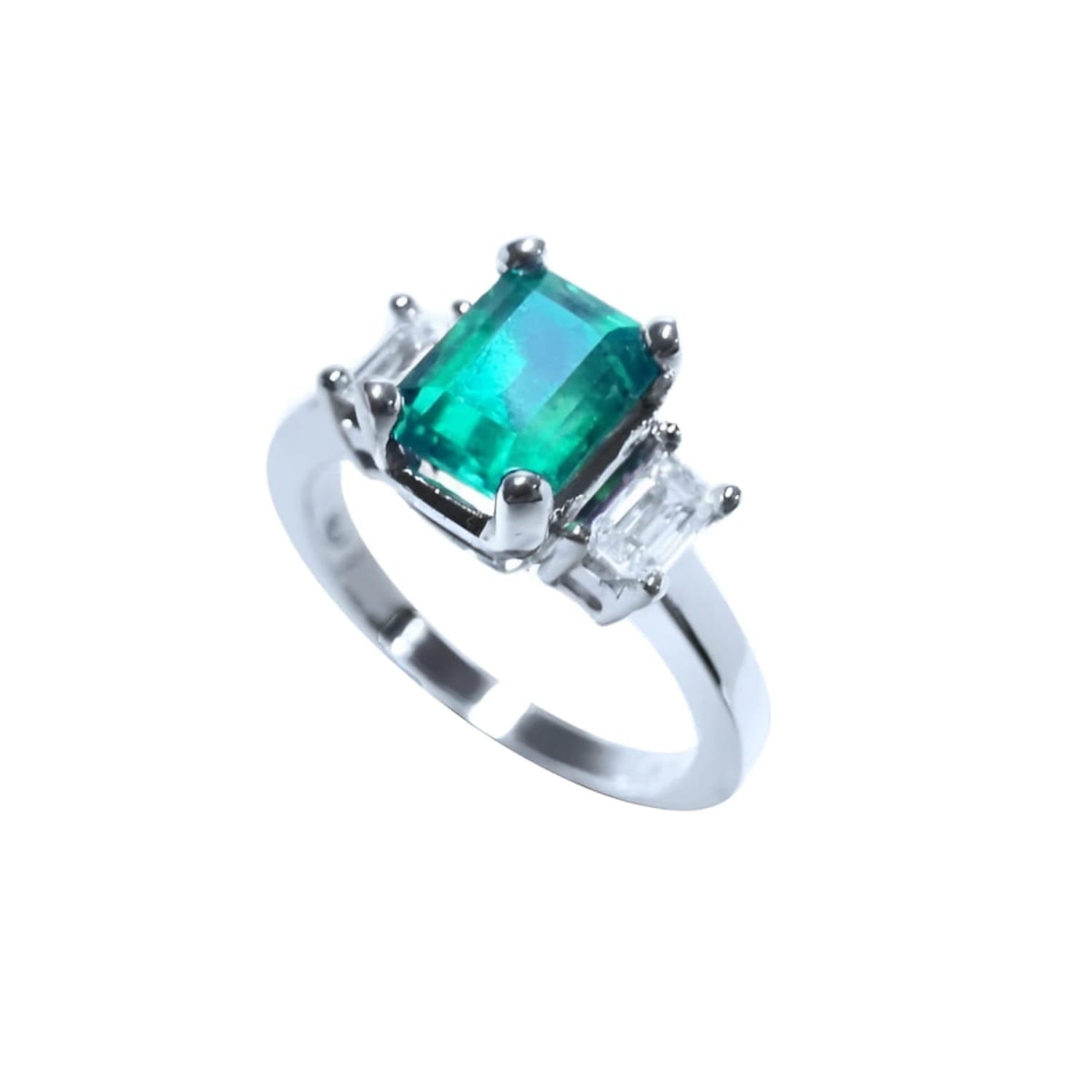 18K white gold three-stone ring with a vibrant emerald and two emerald-cut side diamonds.