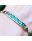 A women's emerald bracelet five premium quality Colombian Emeralds 14k Yellow Gold on a wrist.