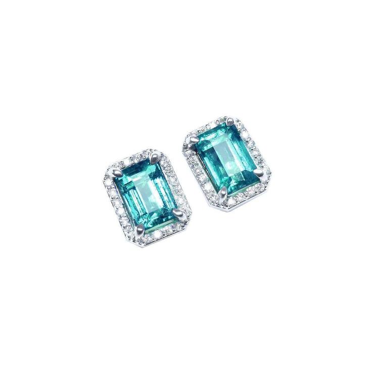 Pair of emerald-cut 14k gold Colombian emerald stud earrings with halo diamond on a right-side position top view.