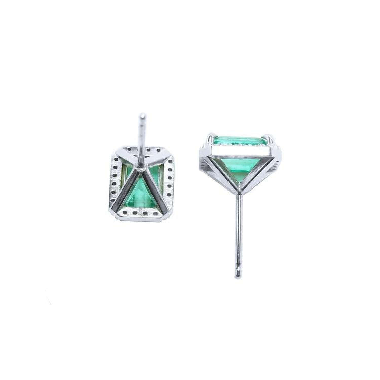 14K white gold emerald-cut stud earrings with vibrant bluish-green emeralds and a diamond halo.
