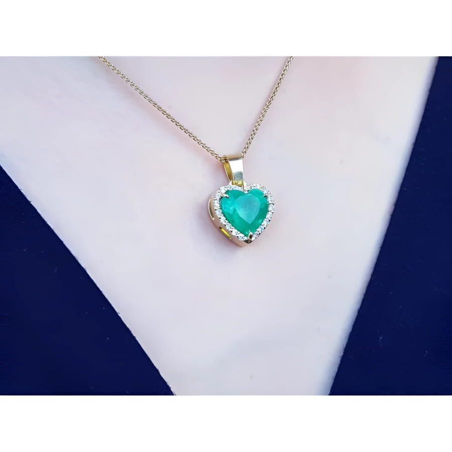 5.04 ct. emerald heart pendant with diamond halo in 18K yellow gold on a woman's neck.