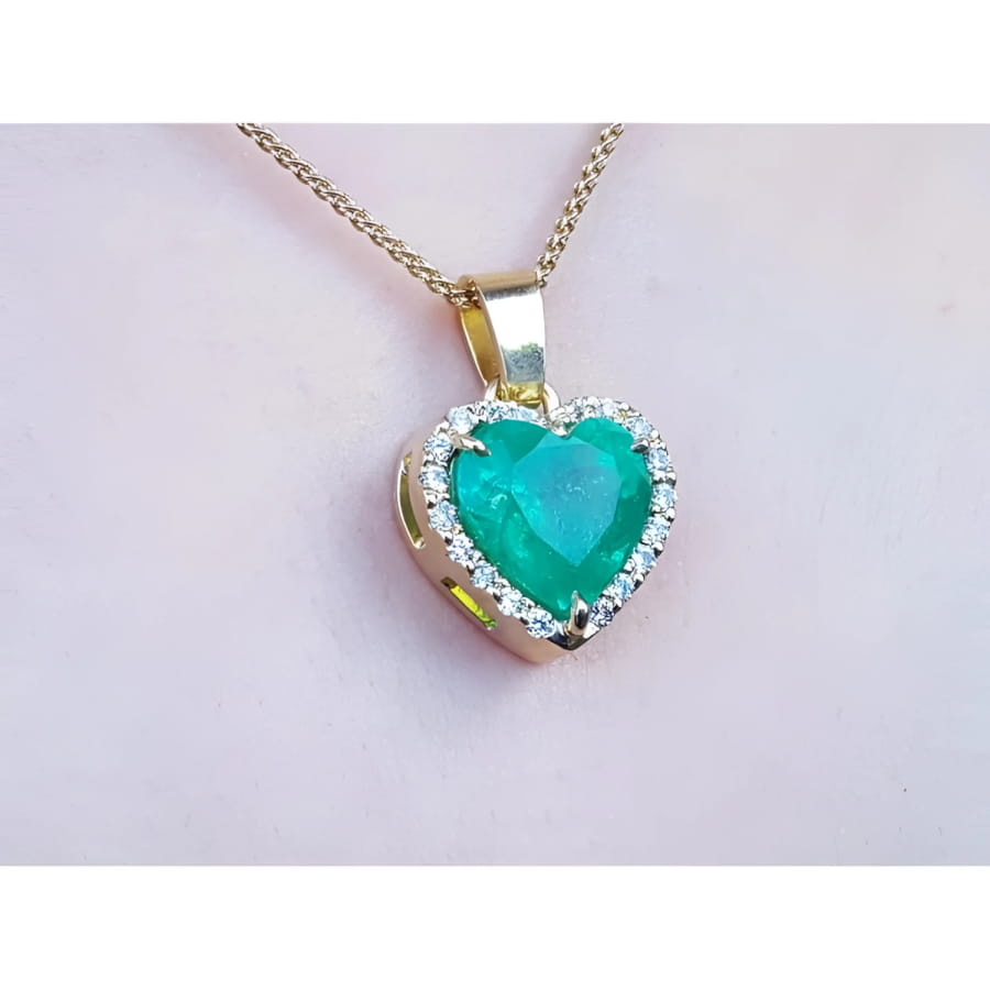 5.04 ct. emerald heart pendant with diamond halo in 18K yellow gold on a gold chain.