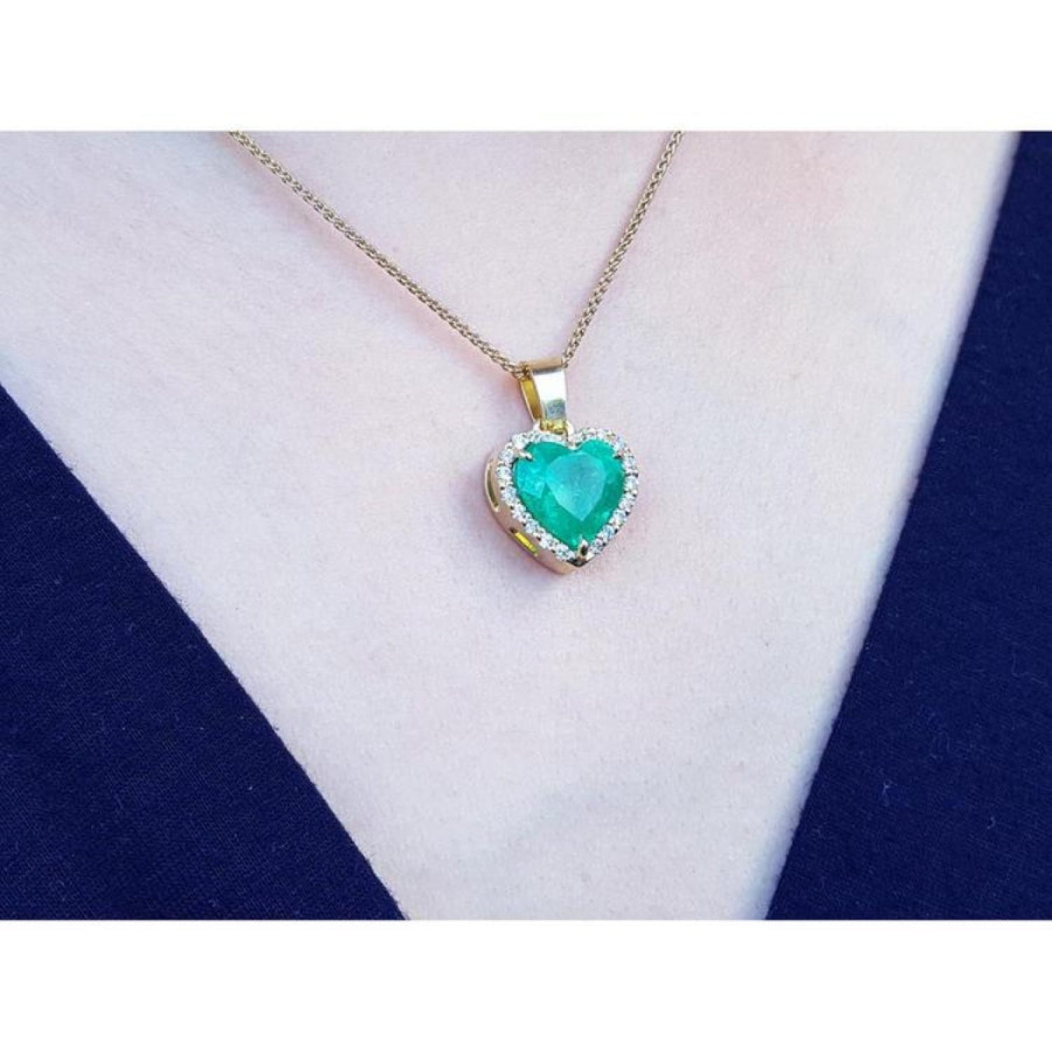 5.04 ct. emerald heart pendant with diamond halo in 18K yellow gold on a woman's neck.