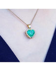 5.04 ct. emerald heart pendant with diamond halo in 18K yellow gold on a woman's neck.