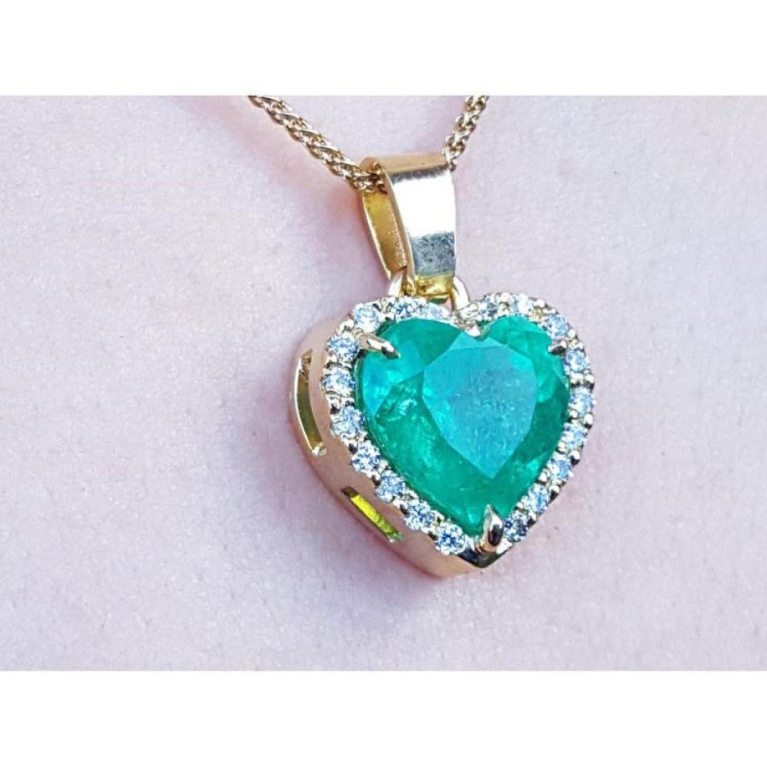 Heart-shaped emerald pendant with gold frame and diamonds made of 18k yellow gold.