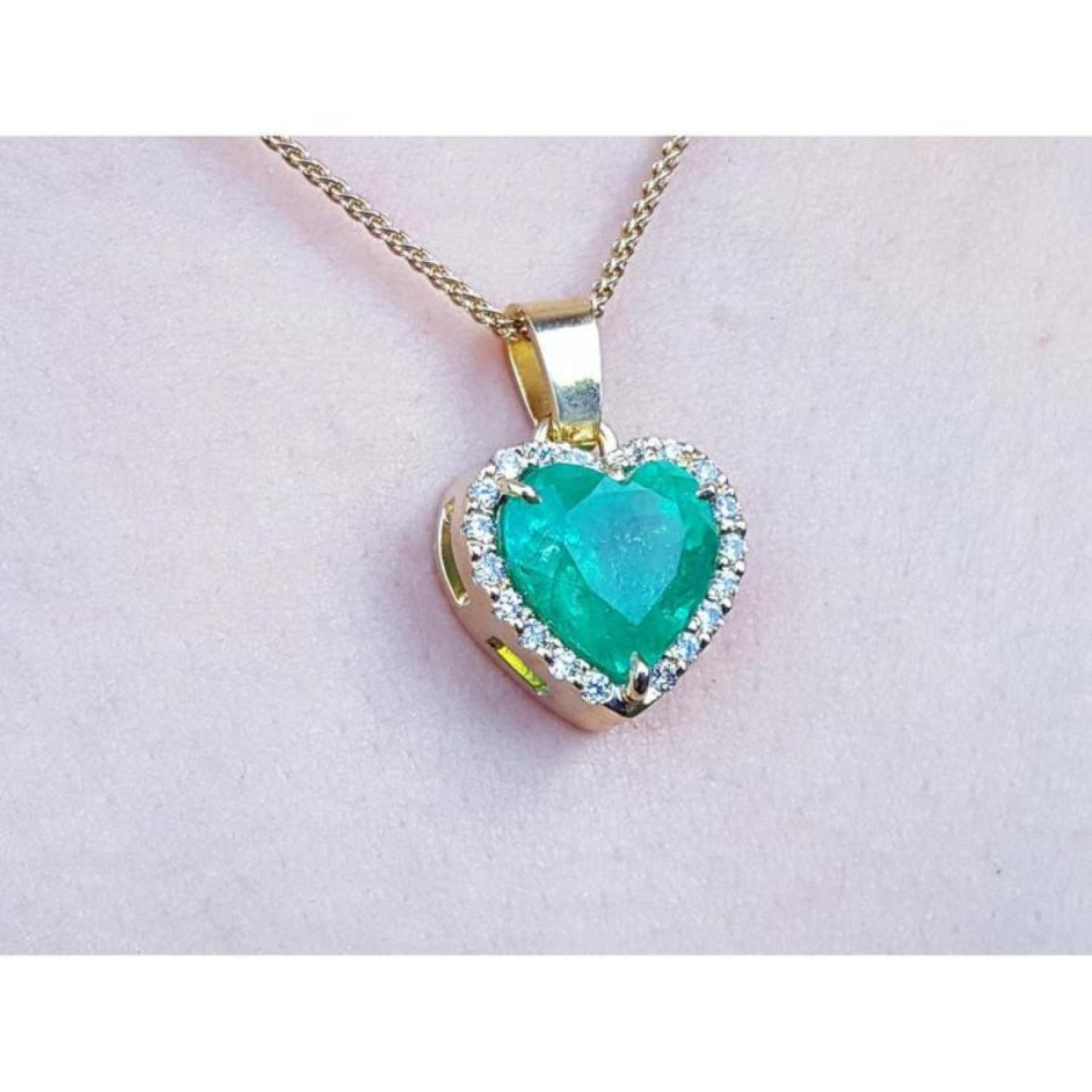 5.04 ct. emerald heart pendant with diamond halo in 18K yellow gold on a gold chain.