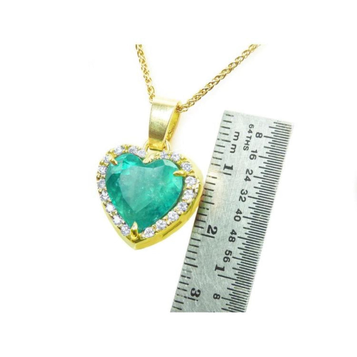 Emerald heart pendant with diamond halo in 18K yellow gold, next to a ruler for scale.
