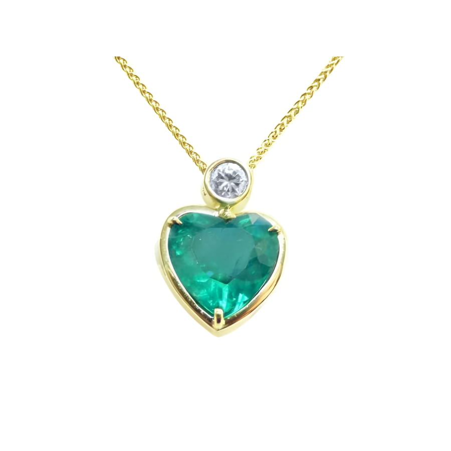 Heart-shaped emerald pendant necklace in 18K yellow gold with a slider bail and bezel-set diamond.
