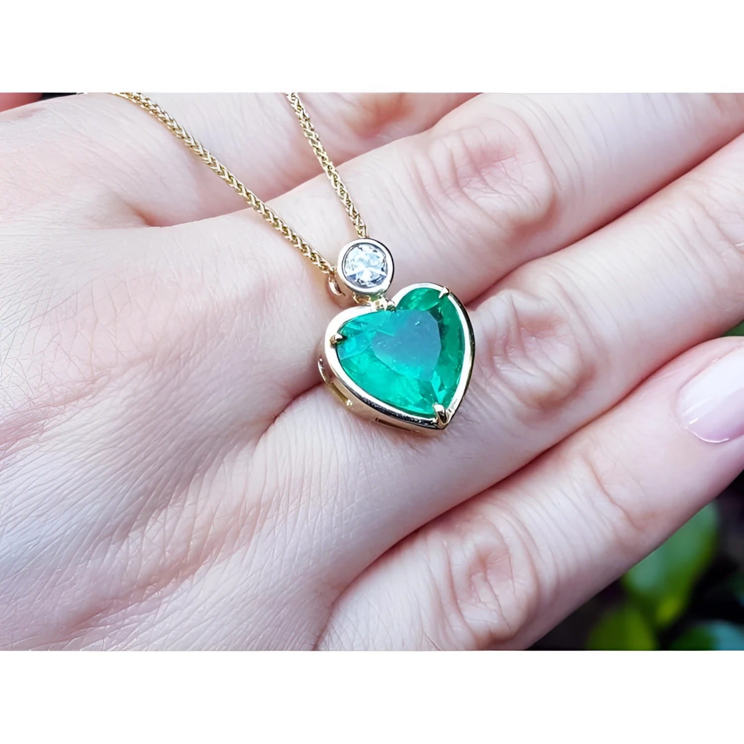 Heart-shaped emerald pendant in 18K yellow gold with a diamond slider bail on a delicate gold chain.