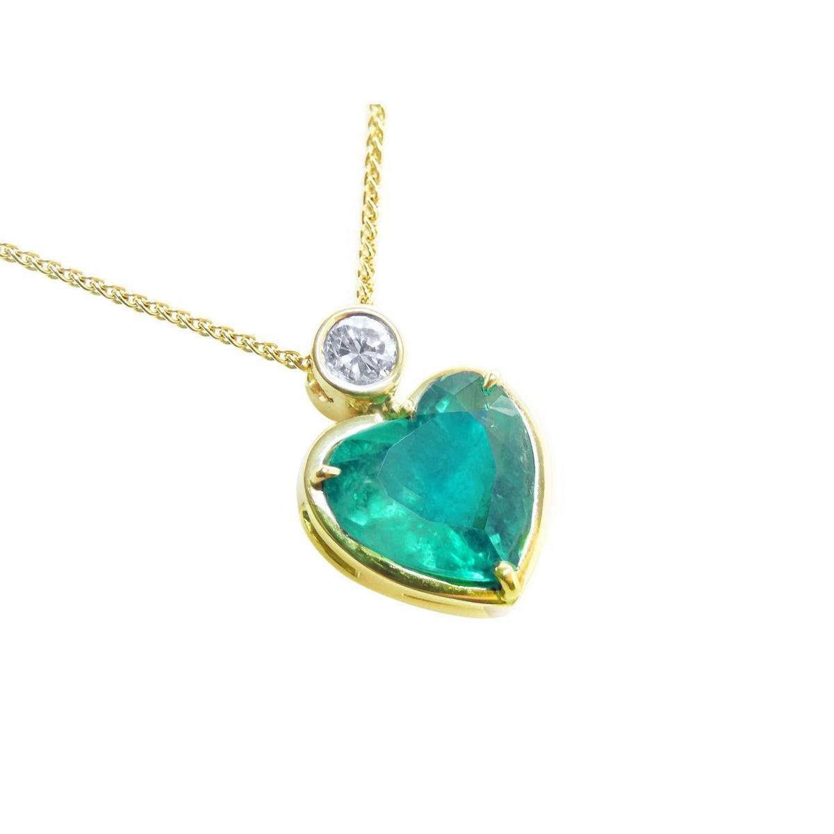 Heart-shaped emerald pendant with gold frame and diamond on a white background