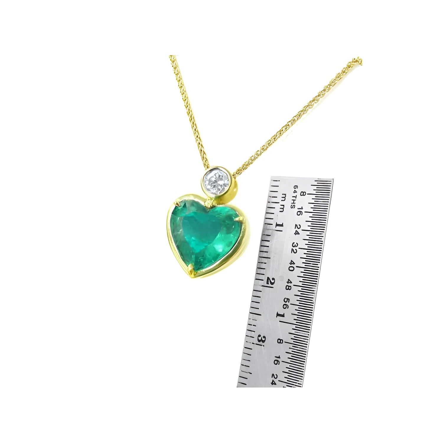 Heart-shaped emerald pendant necklace in 18K yellow gold with a diamond slider bail, shown with a ruler for scale.