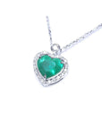 Natural emerald heart pendant in 14K white gold, framed by a halo diamond on a delicate chain.