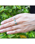 14K white gold journey pendant necklace with three heart-shaped Colombian emeralds on a hand.