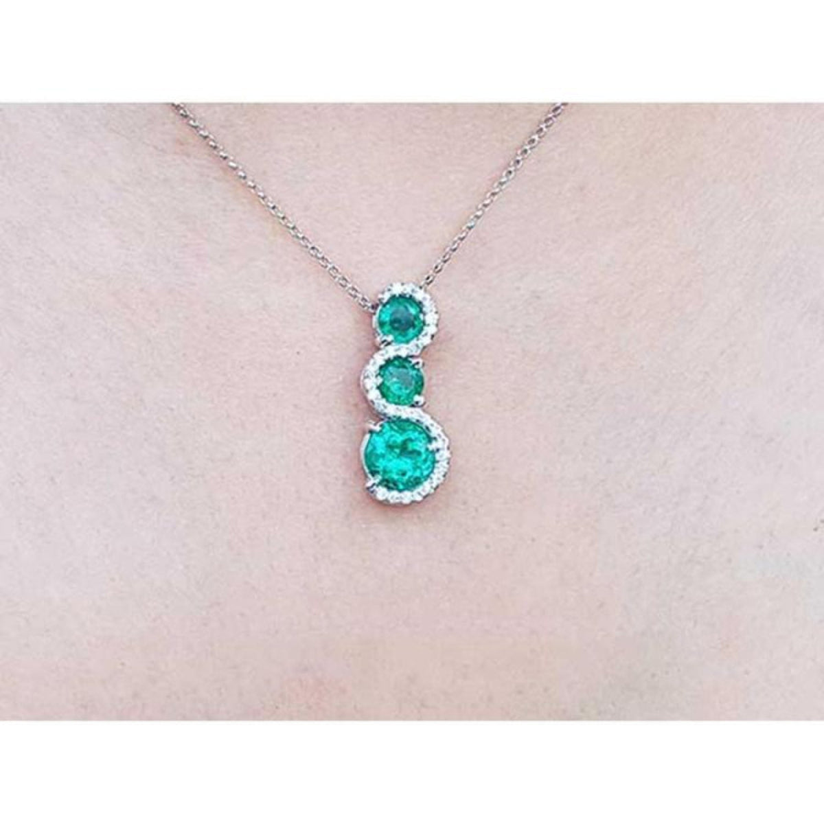 1.99 ct. emerald journey pendant necklace with three round Colombian emeralds and diamonds on a 14K gold chain.