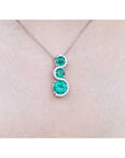 1.99 ct. emerald journey pendant necklace with three round Colombian emeralds and diamonds on a 14K gold chain.