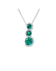 14K white gold emerald journey pendant necklace with three round, deep green emeralds encircled by diamonds.