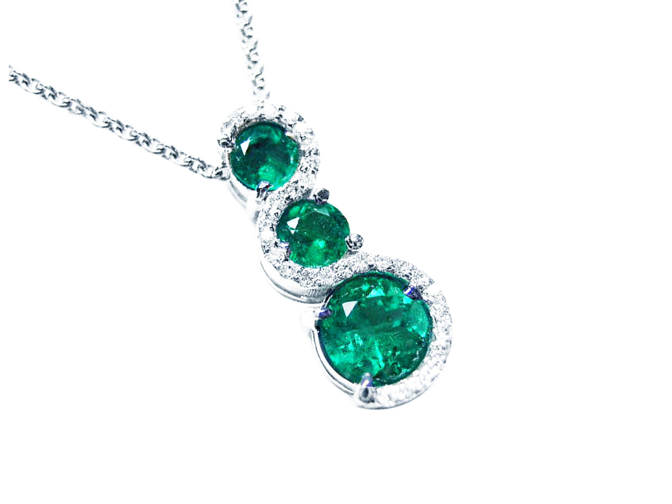 Three round cut natural colombian emeralds pendant journey necklace on a topside view position.