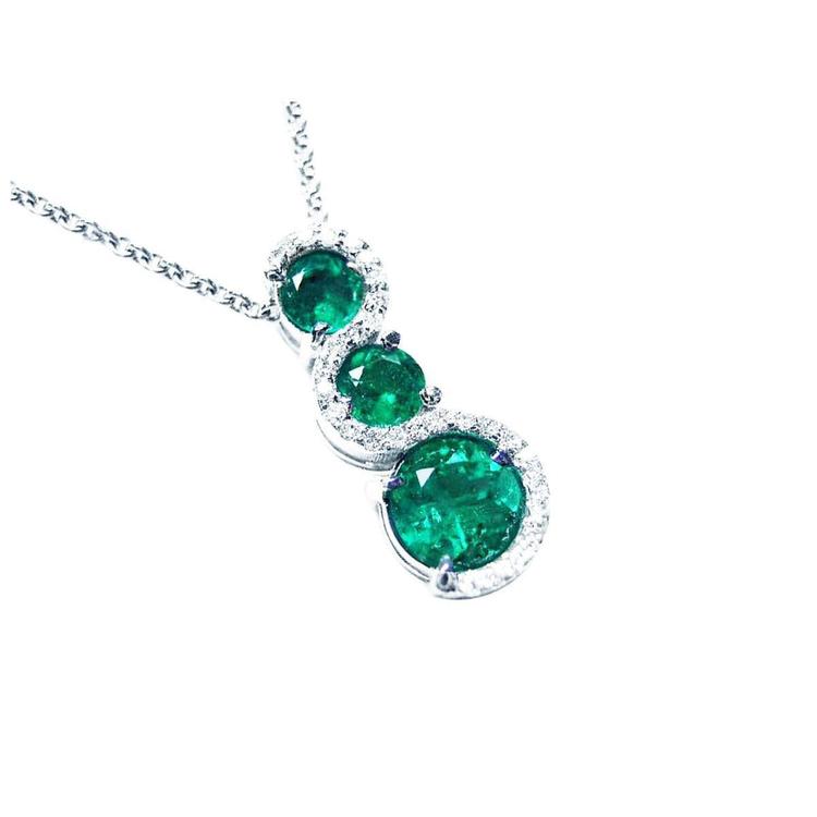 Three round cut natural colombian emeralds pendant journey necklace on a topside view position.