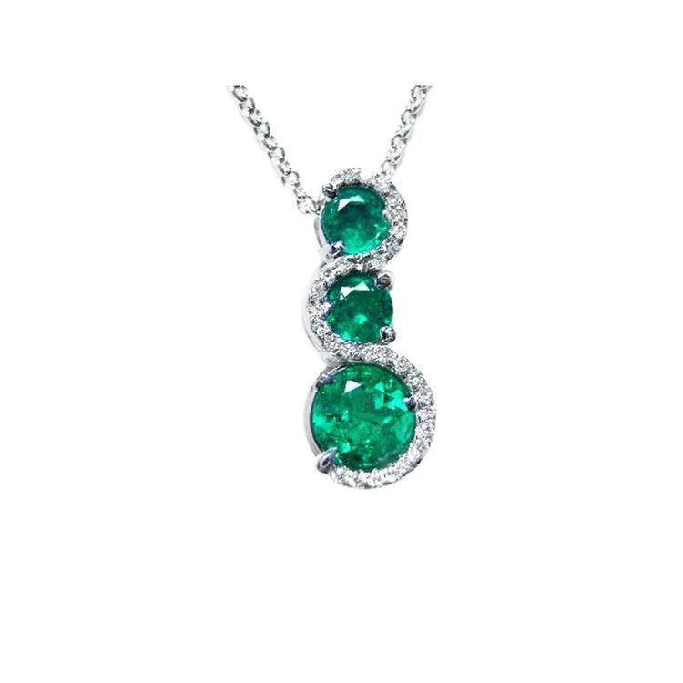 Three round cut natural colombian emerald pendant journey necklace with white gold chain on a topside view position.