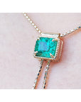 Emerald-cut natural Muzo Colombia emerald lariat necklace in 14K gold with milgrain detail on a box chain.