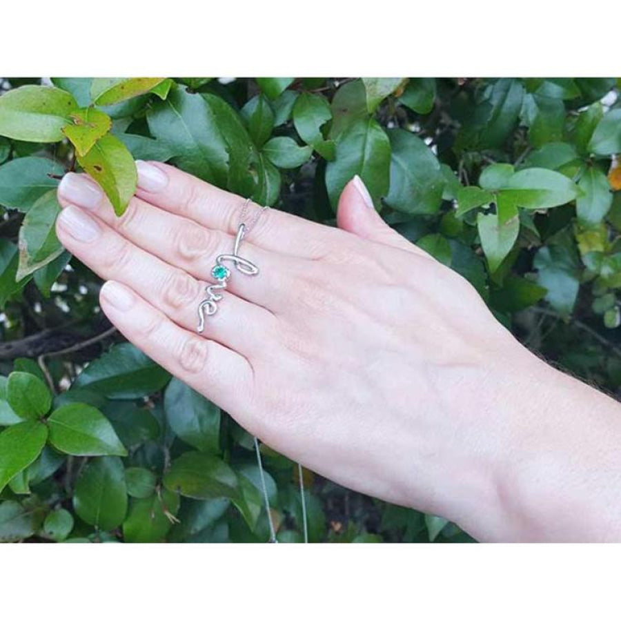 14K white gold "love" script pendant necklace with a round Colombian emerald, worn on a hand.