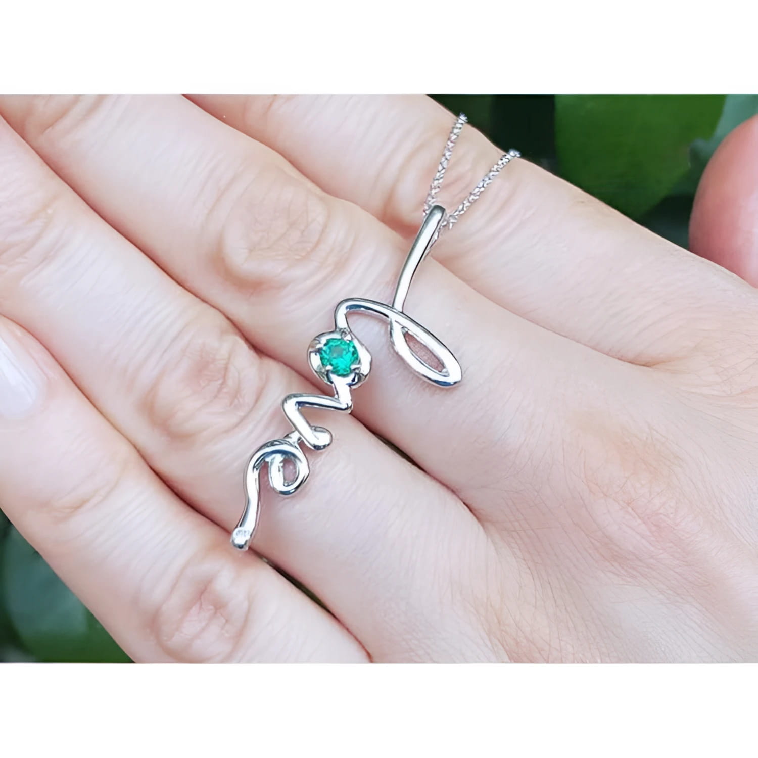 14K white gold "love" script pendant necklace with a round Colombian emerald.