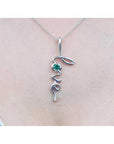 14K white gold "Love" script pendant necklace with a round cut Colombian emerald.